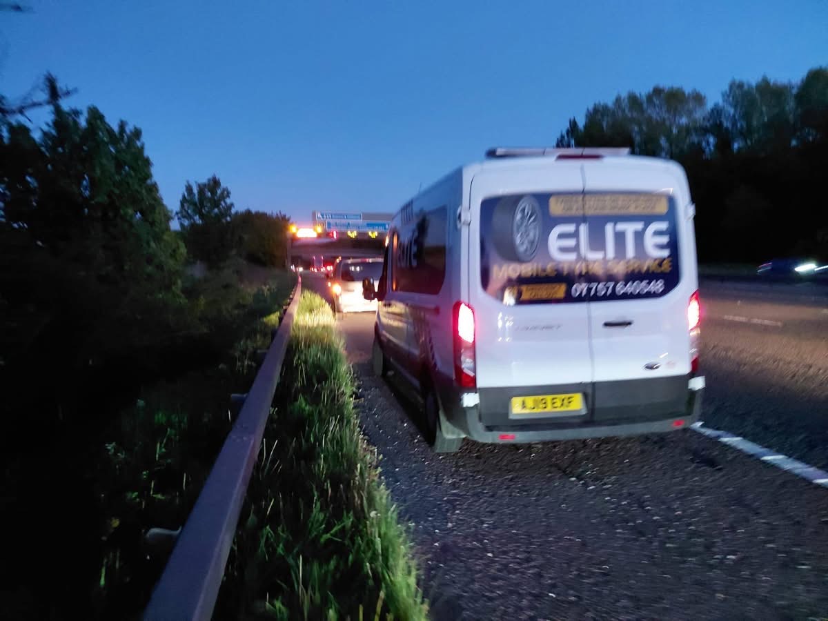 24 hour emergency tyre fitting after dark — Elite Mobile Tyre Service van on a UK motorway hard shoulder at dusk with hazard lights on