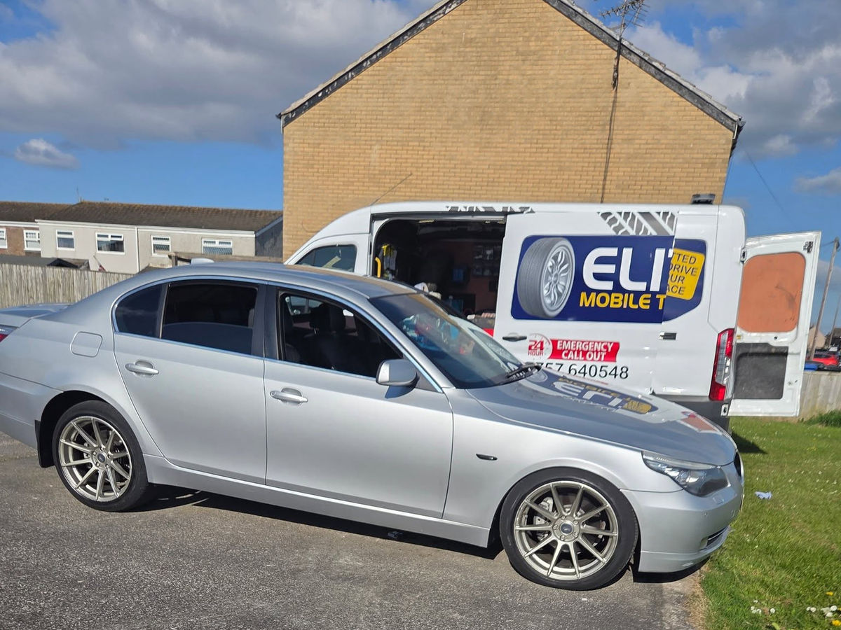 Commercial van assisting a silver car that has broken down.