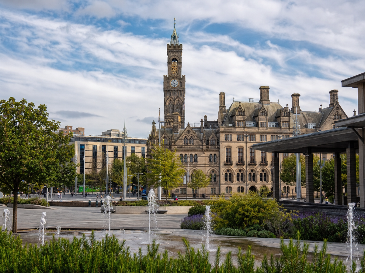 Historic building with clock tower behind a landscaped plaza and fountains.